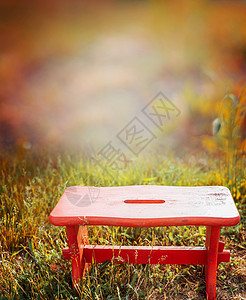 秋天花园草地上的红色小木凳,自然背景图片