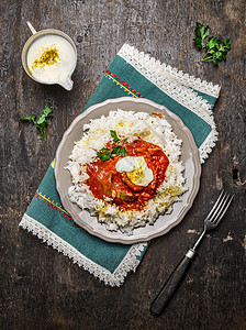 鸡茄炖与巴斯马蒂大米与酸奶酱盘子叉子木制背景,顶部视图图片