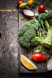 堆新鲜的绿色西兰花与蔬菜成分黑暗的乡村木制背景,健康的烹饪饮食观念图片