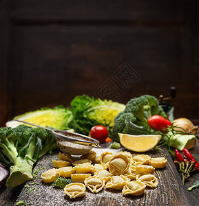 黑木背景的乡村厨房桌子上用植物成分制作的Tortellini意大利食品图片