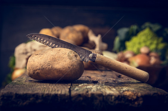 土豆与刀乡村木桌上,厨房场景,健康纯素食品的图片