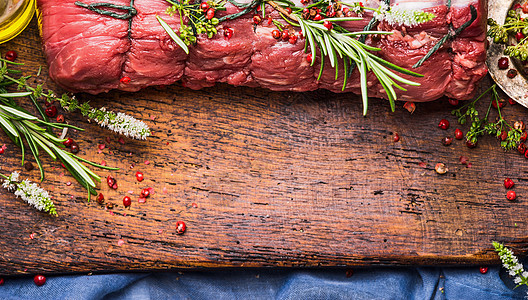 生烤牛肉,香草香料,用绳子绑木制背景上图片
