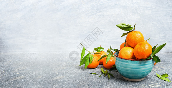 新鲜橘子与绿叶蓝色碗乡村背景图片