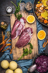 生鸭胸配美味烹饪的原料橙子蔬菜饺子红甘蓝深色乡村厨房桌子上的砧板上,顶部景色德国菜的图片