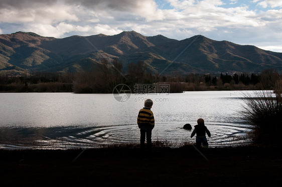 两个男孩个山湖上剪影图片