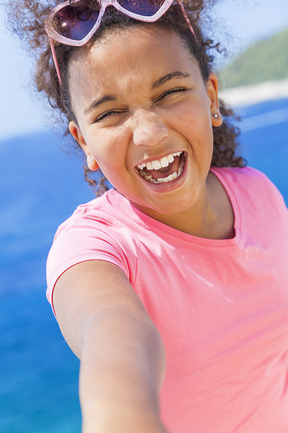自拍照片笑快乐混合种族非裔美国女女孩戴太阳镜明亮的阳光下度假蓝色热带海洋图片