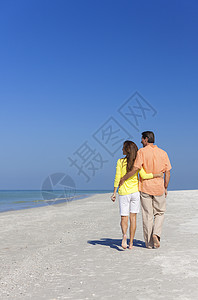 男人女人浪漫的夫妇片荒凉的热带海滩上散步,天空清澈明亮背景图片