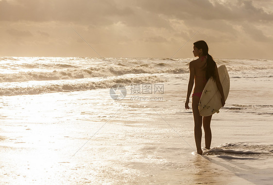 美丽感的轻女子冲浪女孩比基尼与白色冲浪板海滩日落日出图片
