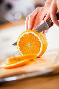 女人的手厨房里切新鲜的橘子图片