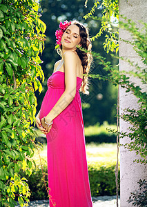 满意的轻孕妇摆着粉红色的花图片