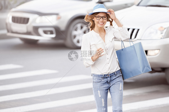 快乐的轻女学生穿过街道,带着咖啡杯小费帽子城市背景下图片