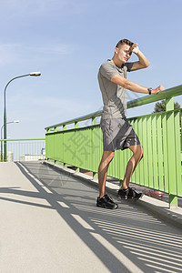 慢跑后,疲惫的男人桥上擦汗图片
