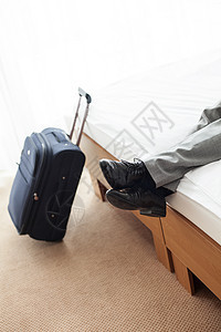 低段商人躺床上,行李放酒店房间的地板上图片