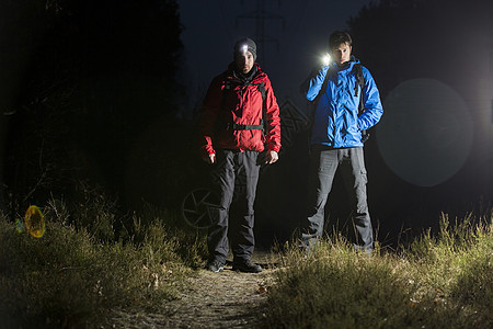 夜间野外用手电筒拍摄的男徒步旅行者的全长肖像图片