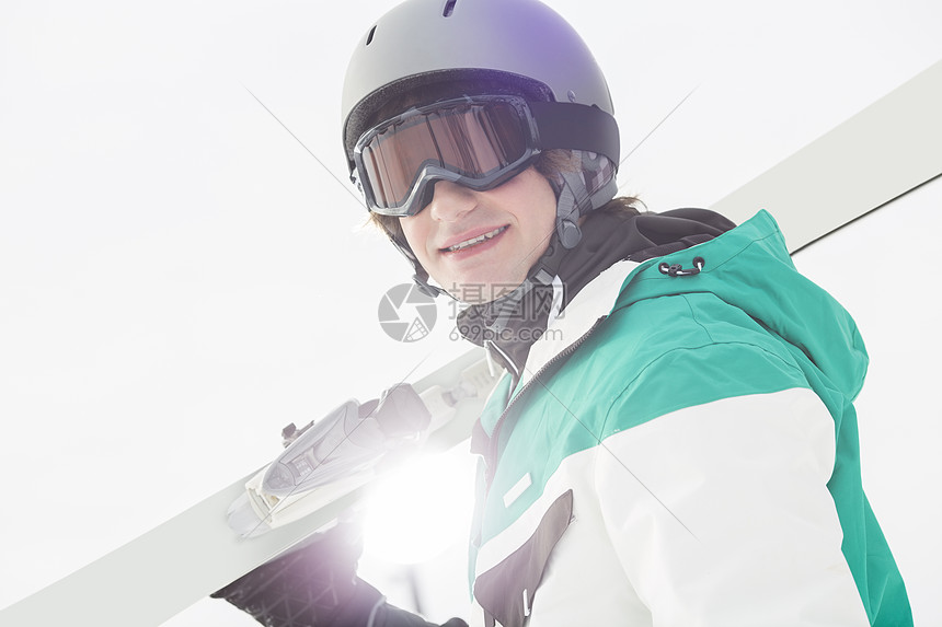 微笑的轻人晴朗的天空上扛着滑雪板的肖像图片