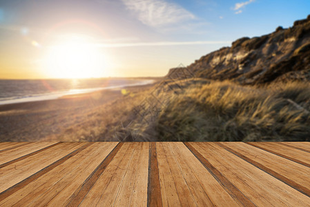 景观充满活力的日落海滩悬崖与广告镜头耀斑效果与木制木板地板图片