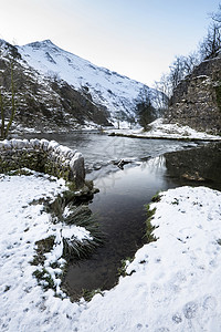 流经雪的河流覆盖了山谷中的冬季景观图片