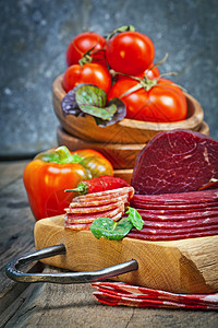 美味的意大利火腿意大利腊肠片木制砧板上,蔬菜草药烹饪传统火腿图片