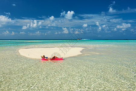 女人海滩上躺充气床垫上放松背景图片