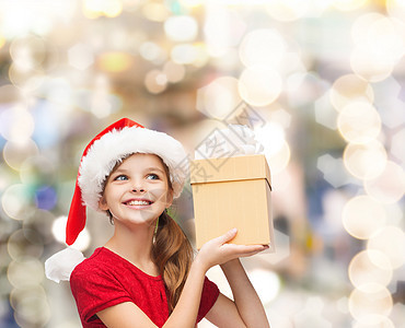 诞节,假日,童人的微笑的女孩诞老人帮助帽子与礼品盒灯光背景图片