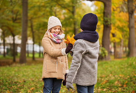 童,季节人的微笑的小女孩男孩与秋天的叶子公园图片