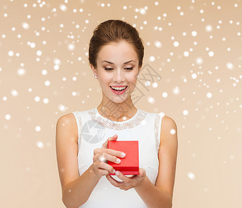 节日,礼物,婚礼幸福的微笑的女人穿着白色连衣裙,着红色的礼品盒米色背景上,米色背景雪图片