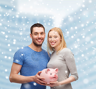 金融,金钱,人家庭的微笑的夫妇持大储蓄罐雪城中心的背景图片