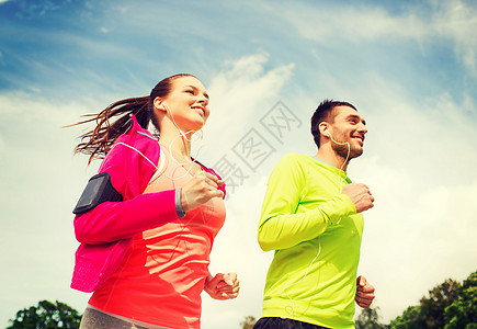 健身,运动,友谊生活方式的微笑夫妇与耳机运行户外图片