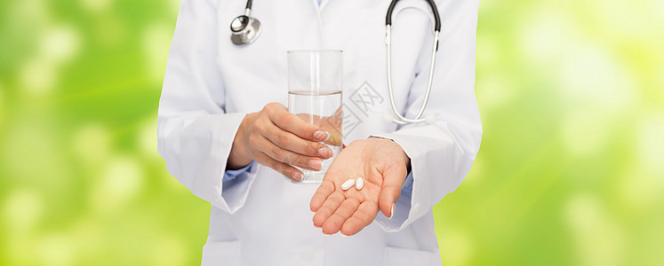 医疗保健,医学,人药房的密切医生与听诊器提供药丸水的绿色背景图片