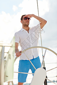 度假,旅行,海洋人的轻人戴着太阳镜方向盘,游艇上看着很远图片