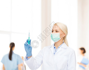 医疗保健医学戴口罩手套的女医生着蓝色背景的注射器图片