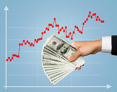 商业金融人投资财富蓝色背景外汇增长图表上,男股票经纪人手握美元现金的特写图片
