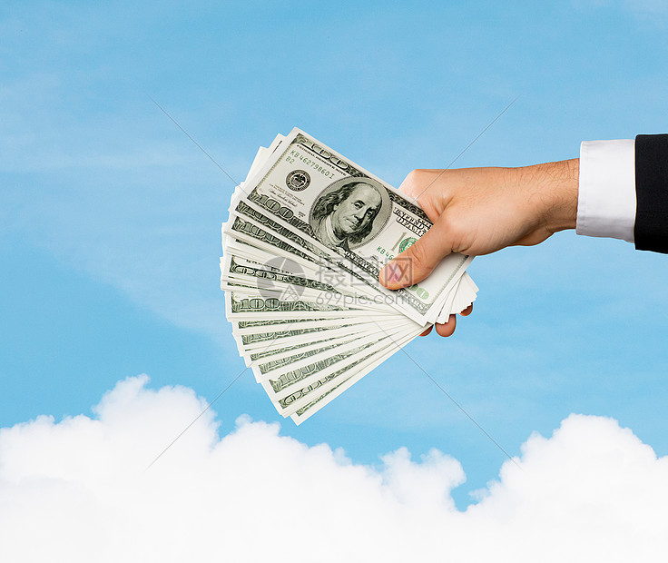 财务人员储蓄财富密切男手中持美元现金的蓝天云背景图片