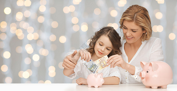 人,财政,家庭预算储蓄快乐的母亲女儿与猪罐纸币灯光背景图片