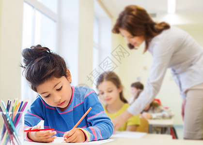 教育,小学,孩子,创造力人的快乐的小女孩用彩色铅笔教室教师背景上画画图片
