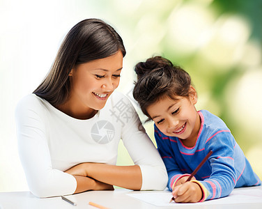 家庭,孩子,创造力快乐的人的快乐的母亲女儿用铅笔画绿色背景图片
