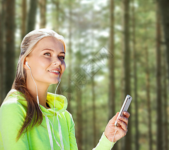 人,运动,健身技术快乐的女人与智能手机耳机听音乐树林背景图片