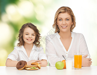 人们,健康的生活方式,家庭食物的快乐的母亲女儿绿色背景下吃健康的早餐图片
