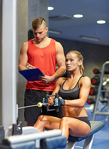 运动,健身,队合作人的轻的女人私人教练健身房机器上弯曲肌肉图片