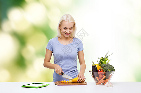 健康饮食,素食,饮食人们的微笑的轻妇女烹饪蔬菜与平板电脑电脑绿色的自然背景图片