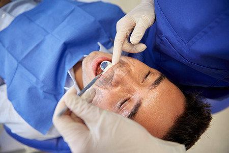 人医学口腔医学保健理念牙科诊所办公室用牙科镜检查男患者的牙齿图片