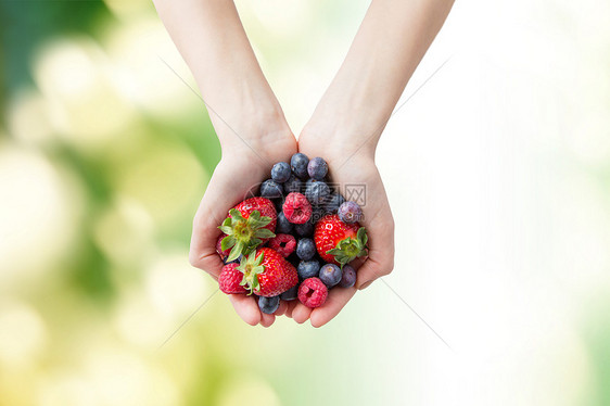 健康的饮食,节食,素食人们的靠近女人的手,着同成熟的夏季浆果绿色的自然背景下图片