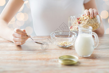 食物,健康饮食,人饮食妇女吃穆斯利与牛奶早餐假日灯光背景图片