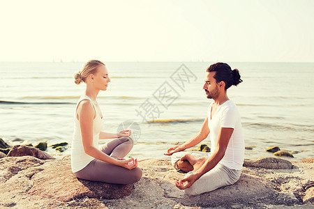 健身,运动,友谊生活方式的微笑夫妇瑜伽练坐沙滩户外图片