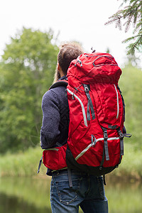冒险,旅行,旅游,徒步旅行人的男子徒步旅行者与红色背包站湖边图片