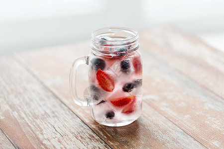 健康的饮食,饮料,饮食排水果水与草莓,黑醋栗蓝莓冰块璃杯桌子上图片
