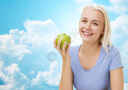 健康饮食,机食品,水果,饮食人的快乐的女人吃绿色的苹果蓝天云彩的背景图片