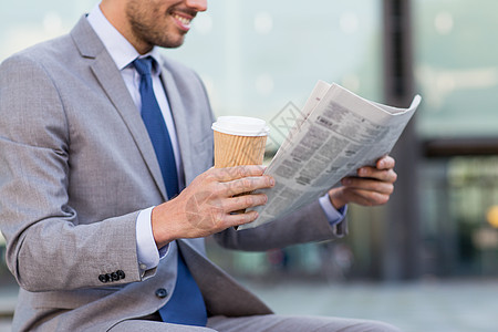 商业,新闻,休息人近距离微笑的商人阅读报纸喝咖啡纸杯超过办公楼背景图片