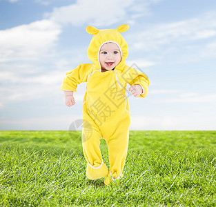 人,孩子,成就幸福的穿着黄色西装的快乐宝宝蓝天草地背景上迈出了步图片