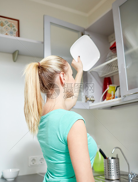 人,家务家务快乐的女人把盘子放厨房橱柜里图片
